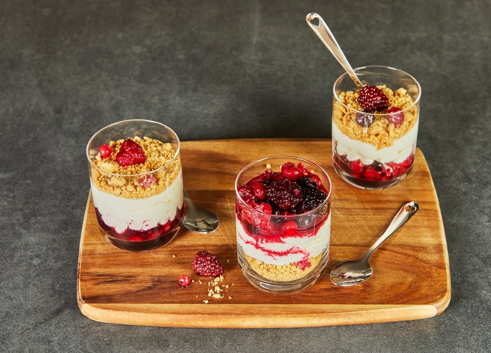 A Close up View Of Three Layered Berry Parfaits In Glasses