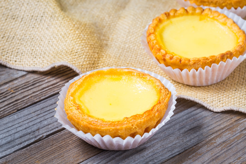 Delicious freshly baked egg tarts on wooden background