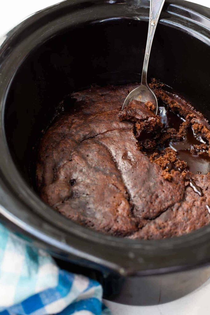 A view of a chocolate lava cake inside a crockpot with a spoon