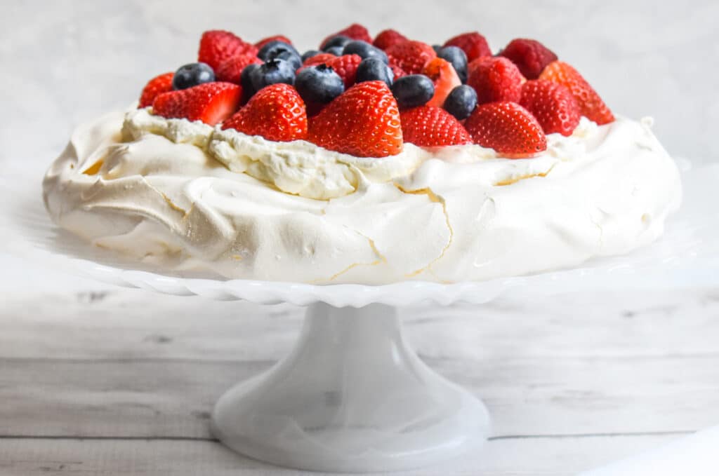 A view of a creamy pavlova gluten free with berry topping on it