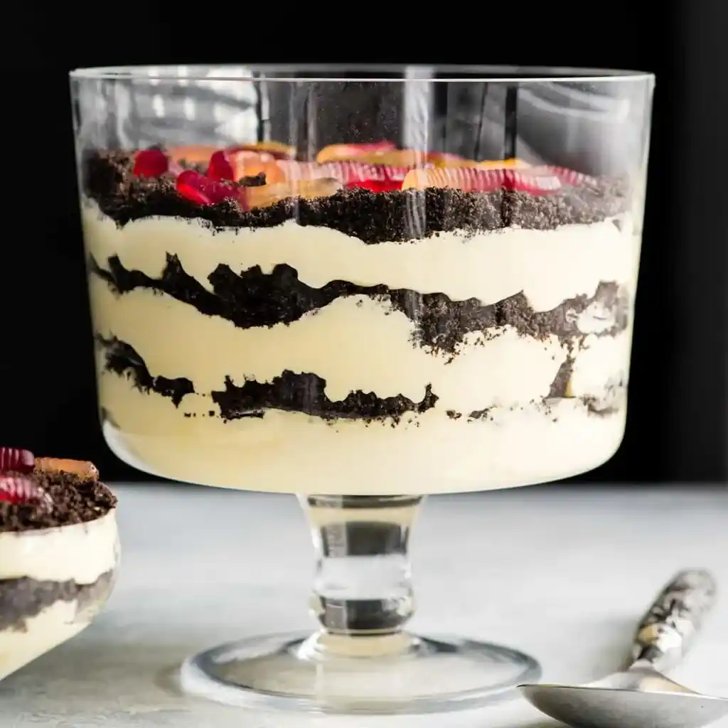 A view of a layered oreo and cream dirt dessert in a glass bowl