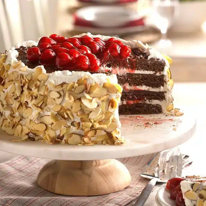 A view of a sliced up black forest chocolate torte with cherries on top