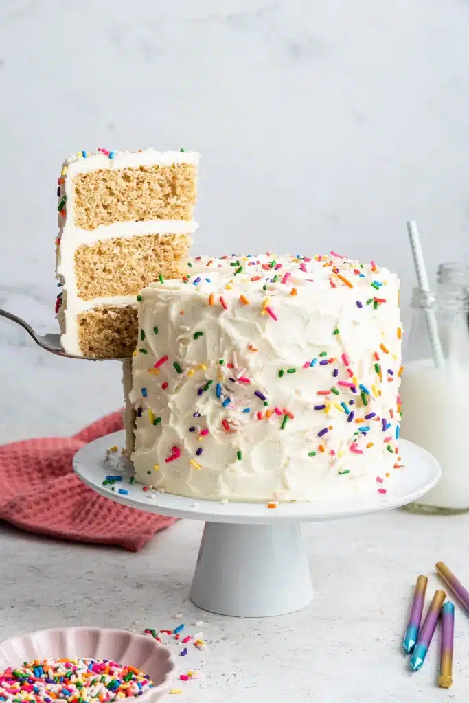 A view of a vanilla frosting birthday cake with sprinkles on it