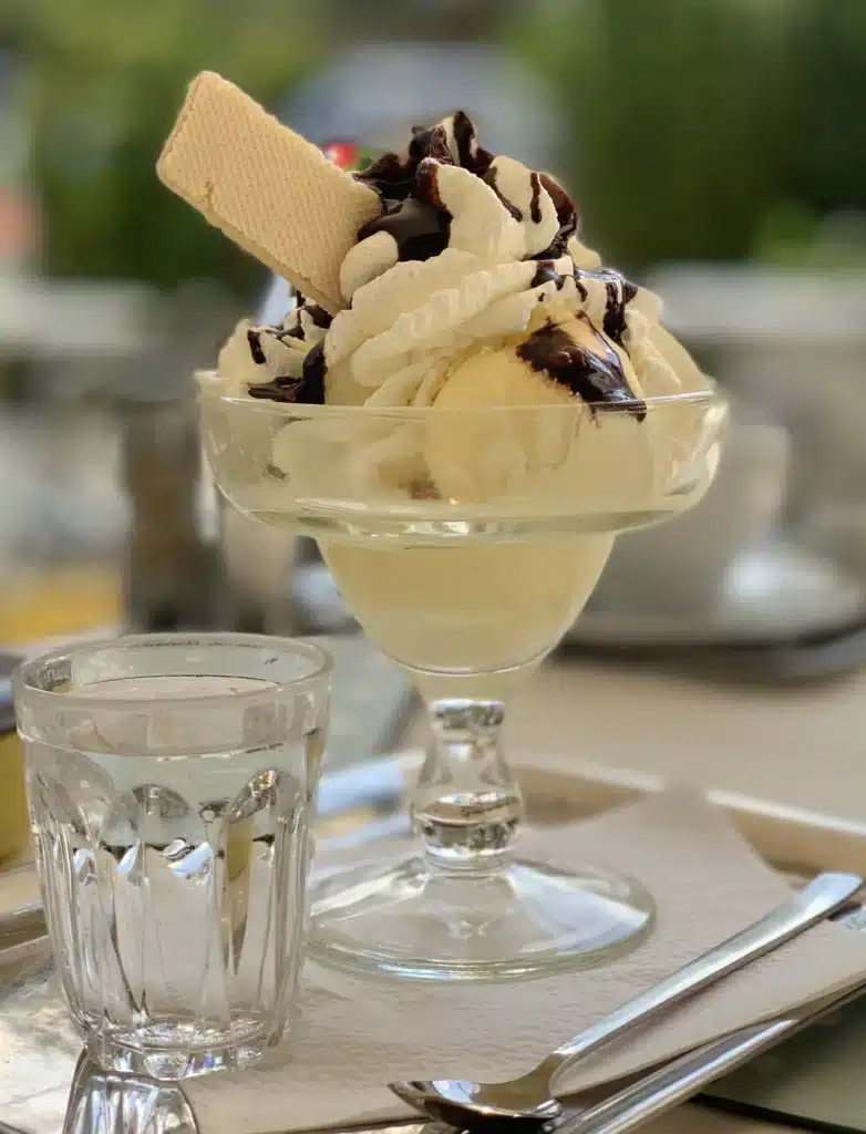 A view of an ice cream delight served in a glass with a wafer on top