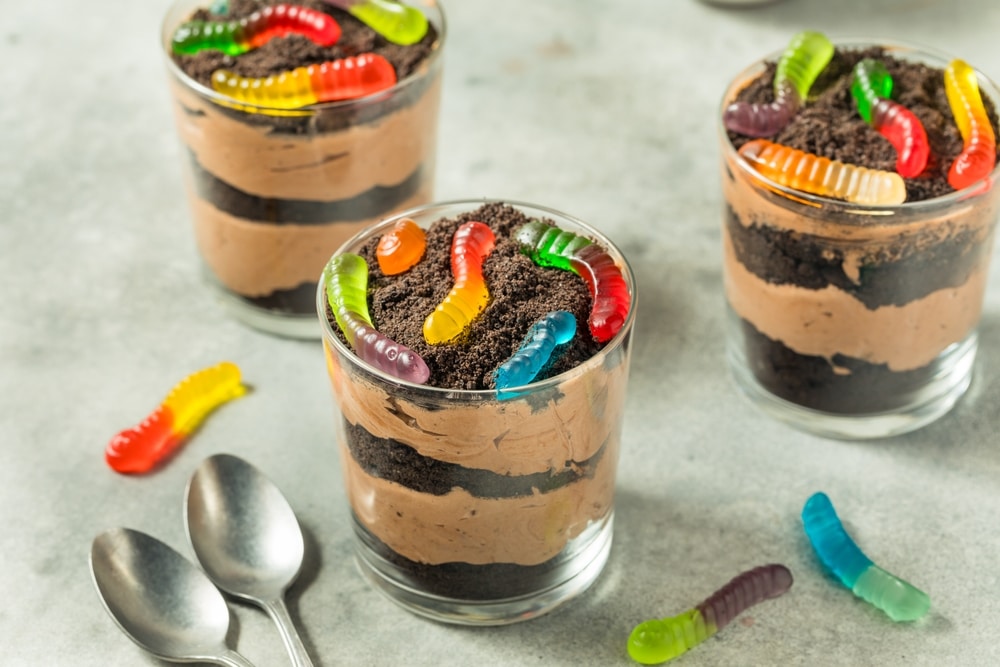 A view of cups of dirt dessert with gummy worms on top