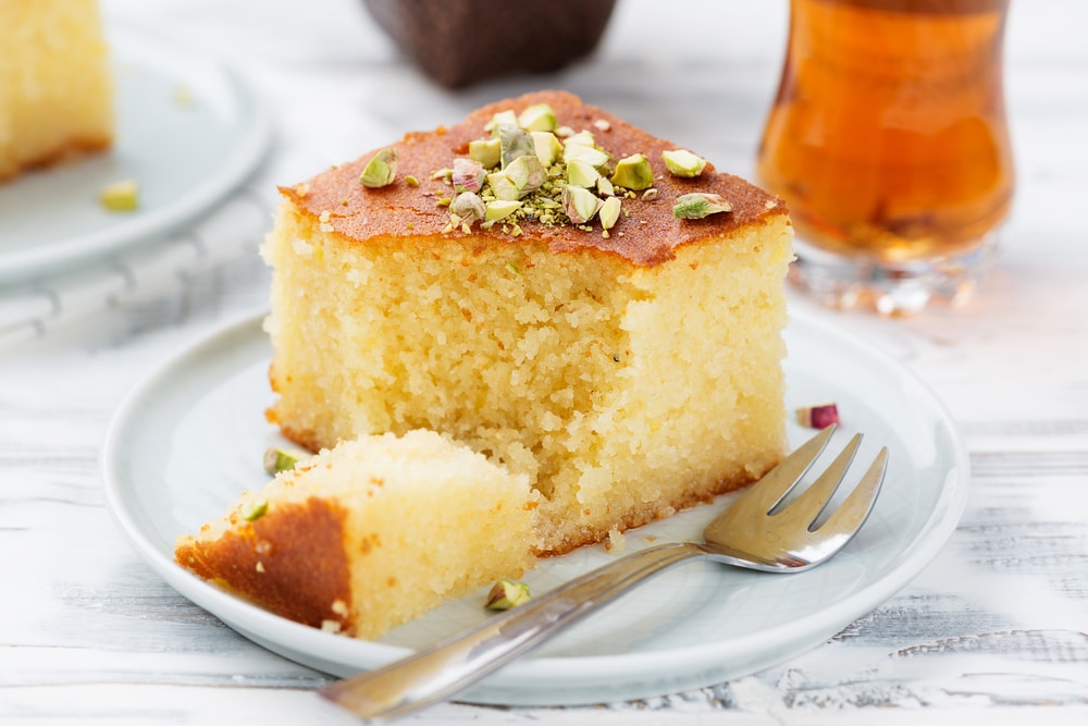 Revani sweet semolina cake with pistachio in plate with a fork