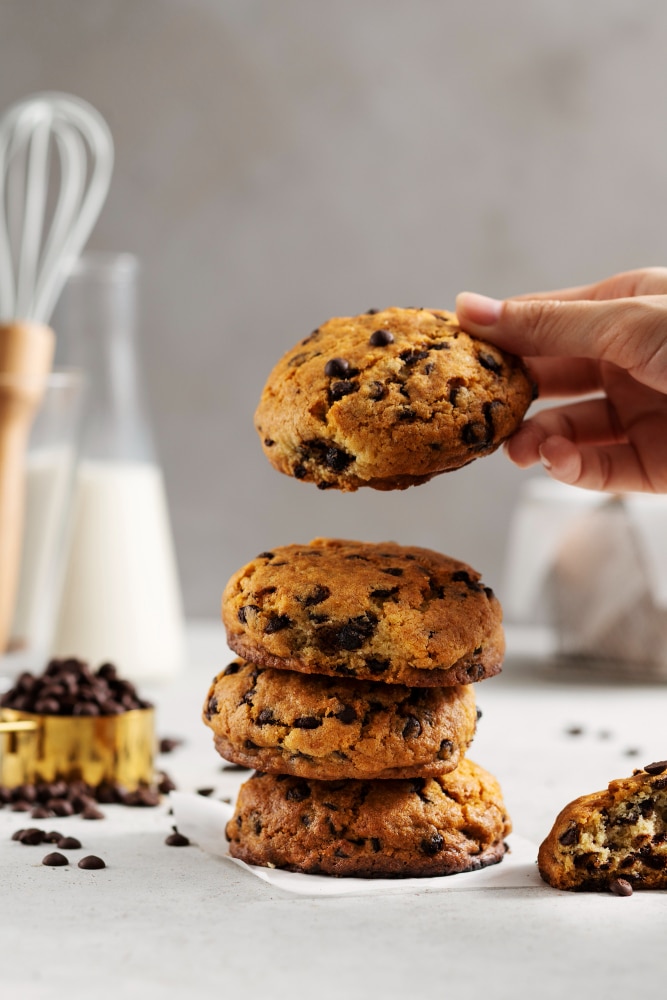 chocolate chips cookies staked and a man holding one cookie