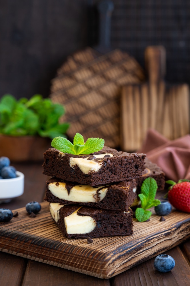 3 cream cheese brownies stacked on one another garnished with mint sprig