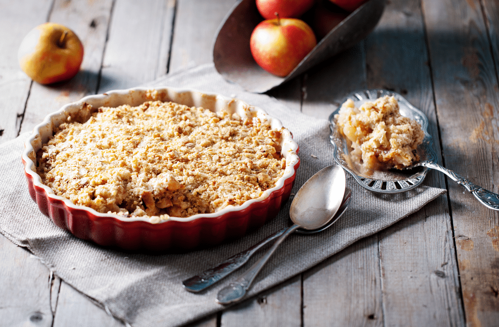 Apple crumble on the wooden background with apples