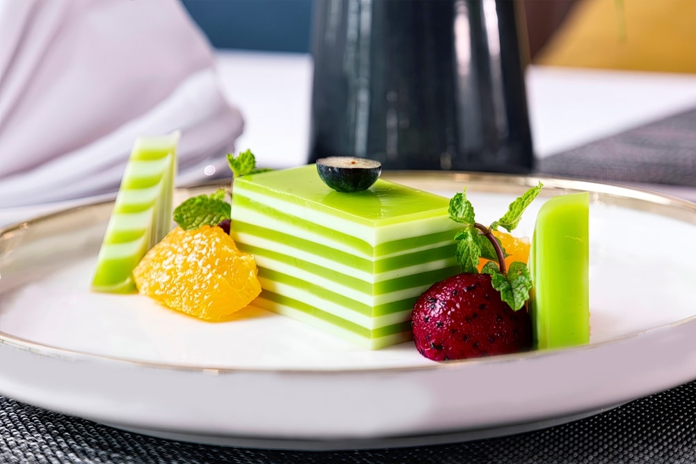 Steamed Coconut pandan Cake (khanom Chan) Decorated With Tropical Fruits Close up