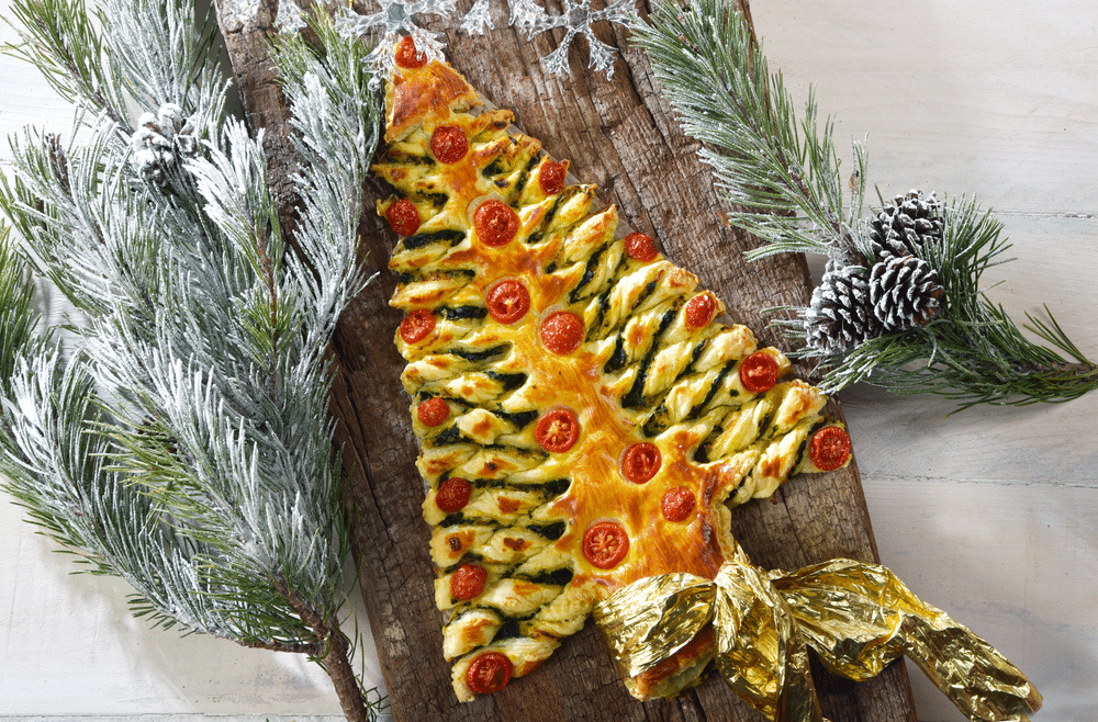 Christmas Tree of puff pastry on to a wooden board with fir branches around