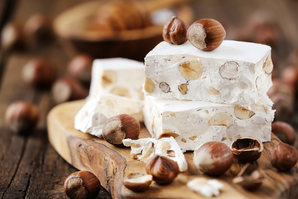 Delicious Italian festive torron or nougat with hazelnuts on wood