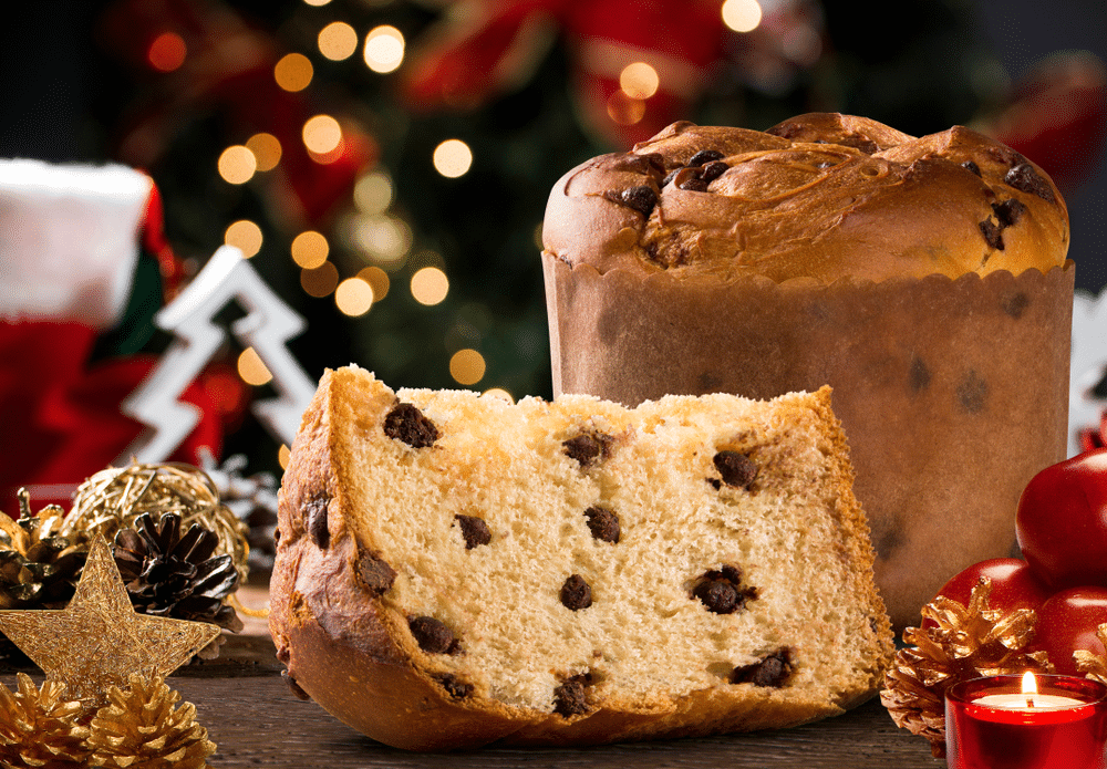 Delicious Panettone slice with candied fruits with blinking blurred christmas lights